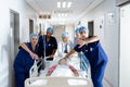 Diverse group of healthcare workers clearing the way for patient in bed in hospital corridor