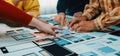 Team Collaborating on Digital Interface Design Strategy with Colorful Mockups, Hands Working Together on Paper Designs Royalty Free Stock Photo