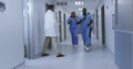 Diverse group of male and female doctors running urgently through hospital corridor