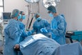 Diverse group of male and female surgeons in operating theatre wearing face masks performing surgery