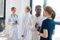 Diverse group of multi-ethnic male and female professional doctors having conversation in clinic standing on background Royalty Free Stock Photo