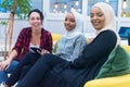 Diverse group of multiethnic young businesswomen working as a team. Two Muslim hijab and one american female co workers discussing