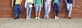 Diverse group of young men and women in casual clothes standing by brick wall in street Royalty Free Stock Photo