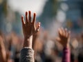 Diverse group of people raising their hands outdoors in daylight signaling participation and unity during a public event or Royalty Free Stock Photo