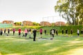 Diverse group of people of various ages doing yoga poses in a lush green grassy field