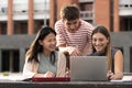Diverse group of people working together with a laptop in campus.Young happy friends studying outside using computer and Royalty Free Stock Photo