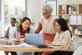 Diverse group of smiling business women using a laptop for a brainstorm meeting in an office. Happy confident Royalty Free Stock Photo