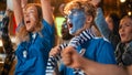 Diverse Group of Soccer Fans with Colored Faces Watching a Live Football Match in a Sports Bar Royalty Free Stock Photo