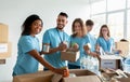 Diverse group of volunteers sorting donated food in boxes, working in community charity donation center and smiling Royalty Free Stock Photo