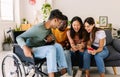 Diverse group of young friends laughing using mobile phone together at home Royalty Free Stock Photo