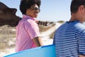 A diverse group of young friends walks to the beach, one of them, an African American man, plays gui Royalty Free Stock Photo