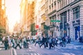 Diverse groups of people walk across the crowded intersection of Broadway and Spring Street in the SoHo neighborhood of Manhattan