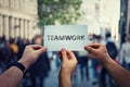 Diverse hands holding together a paper with teamwork text. Group of three people unity and team concept as business metaphor for Royalty Free Stock Photo