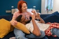 Multi ethnic happy couple man and woman look at phone lying on couch in living room. Royalty Free Stock Photo