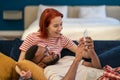 Multi ethnic happy couple man and woman look at phone lying on couch in living room. Royalty Free Stock Photo