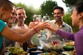 Diverse happy friends toasting with wine and beer during garden dinner party. Friends having fun. Royalty Free Stock Photo