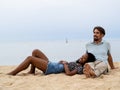 Diverse heterosexual couple sitting affectionately on the beach. Couple in love, honeymoon