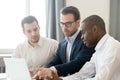 Diverse interns listening to mentor pointing at laptop screen