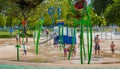 Diverse kids enjoy water splash pad or sprayground at Park Playground. Water fountain activities for child and parent