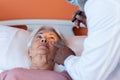 Diverse male doctor examining eye of senior female patient lying on bed with penlight, copy space Royalty Free Stock Photo