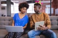 Diverse male and female colleagues working sititng on sofa in office using computer and tablet Royalty Free Stock Photo