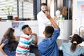 Diverse male teacher and elementary schoolchildren, one raising hand, in biology class Royalty Free Stock Photo