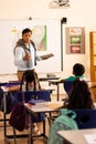 Diverse male teacher using tablet teaching with children at desks in elementary school class Royalty Free Stock Photo