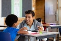 Diverse male teacher using tablet teaching children at desks in elementary school class Royalty Free Stock Photo