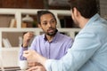 Diverse male workmates discussing collaborative task sit in office workplace