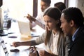 Diverse millennial employees working together using laptop in of