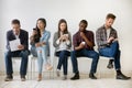 Diverse millennial people waiting in queue holding resumes using