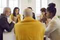 Diverse multicultural group of people sitting around table and praying to God together Royalty Free Stock Photo