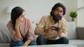 Diverse multiethnic couple at home bored angry arabian woman offend on husband addicted playing console video game with Royalty Free Stock Photo