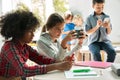 Diverse multiethnic kids school students using smartphones in classroom.