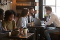 Diverse multiracial young people talking drinking coffee in cozy