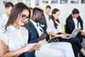 Diverse office people working on mobile phones, corporate employees holding smartphones at meeting. Serious multiracial Royalty Free Stock Photo