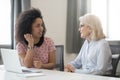 Diverse old and young female colleagues talking at work
