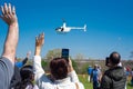 Diverse people hands waving, taking photo hovering helicopter drops colorful eggs, goodies at Easter event, Richardson