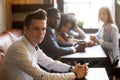 Diverse friends looking at frustrated man sitting alone in cafe