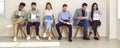 Diverse people sitting by office wall and waiting for business meeting or job interview Royalty Free Stock Photo