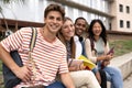Diverse people smiling sitting outside holding folders. Multicultural group of happy students looking at camera with Royalty Free Stock Photo