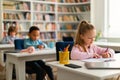 Diverse school children boy and girl sitting at desks in classroom at primary school, writing or drawing in notebooks