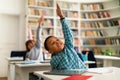 Children at desks raising hands during classroom lesson Royalty Free Stock Photo