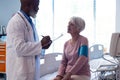 Diverse senior male doctor taking blood pressure of senior female patient in hospital, copy space Royalty Free Stock Photo