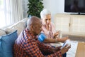 Diverse senior man testing blood pressure of senior woman in sunny living room Royalty Free Stock Photo