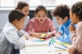 Diverse small schoolchildren using mobile phone at classroom Royalty Free Stock Photo