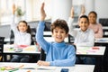 Diverse small schoolkids raising hands at classroom Royalty Free Stock Photo