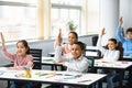 Diverse small schoolkids raising hands at classroom Royalty Free Stock Photo