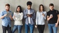 Diverse students with books standing near grey wall