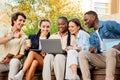 Diverse students friends sitting on bench outdoors in university campus Royalty Free Stock Photo